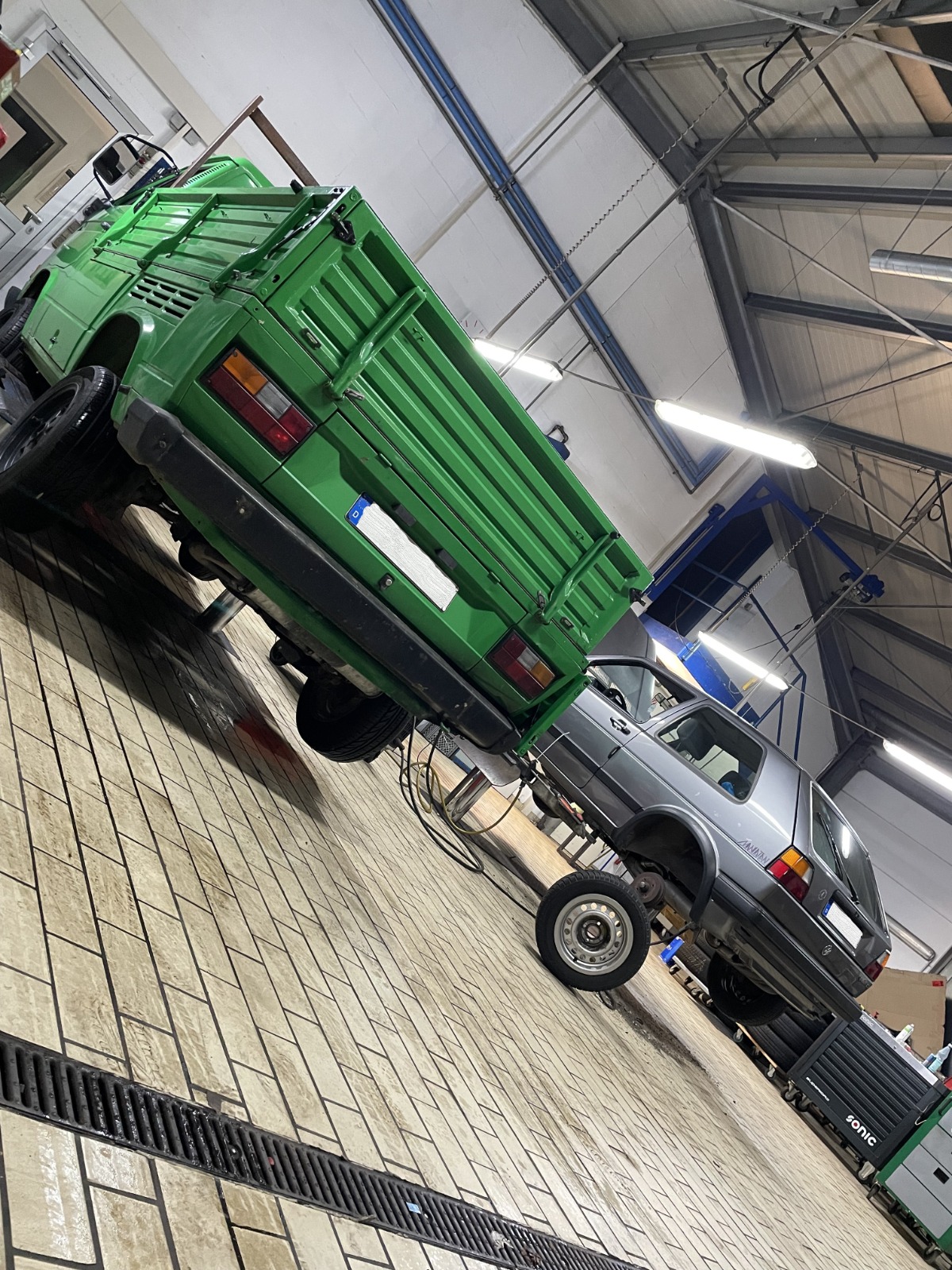 Grüner VW T3 Pritschenwagen und VW Golf in der Werkstatt